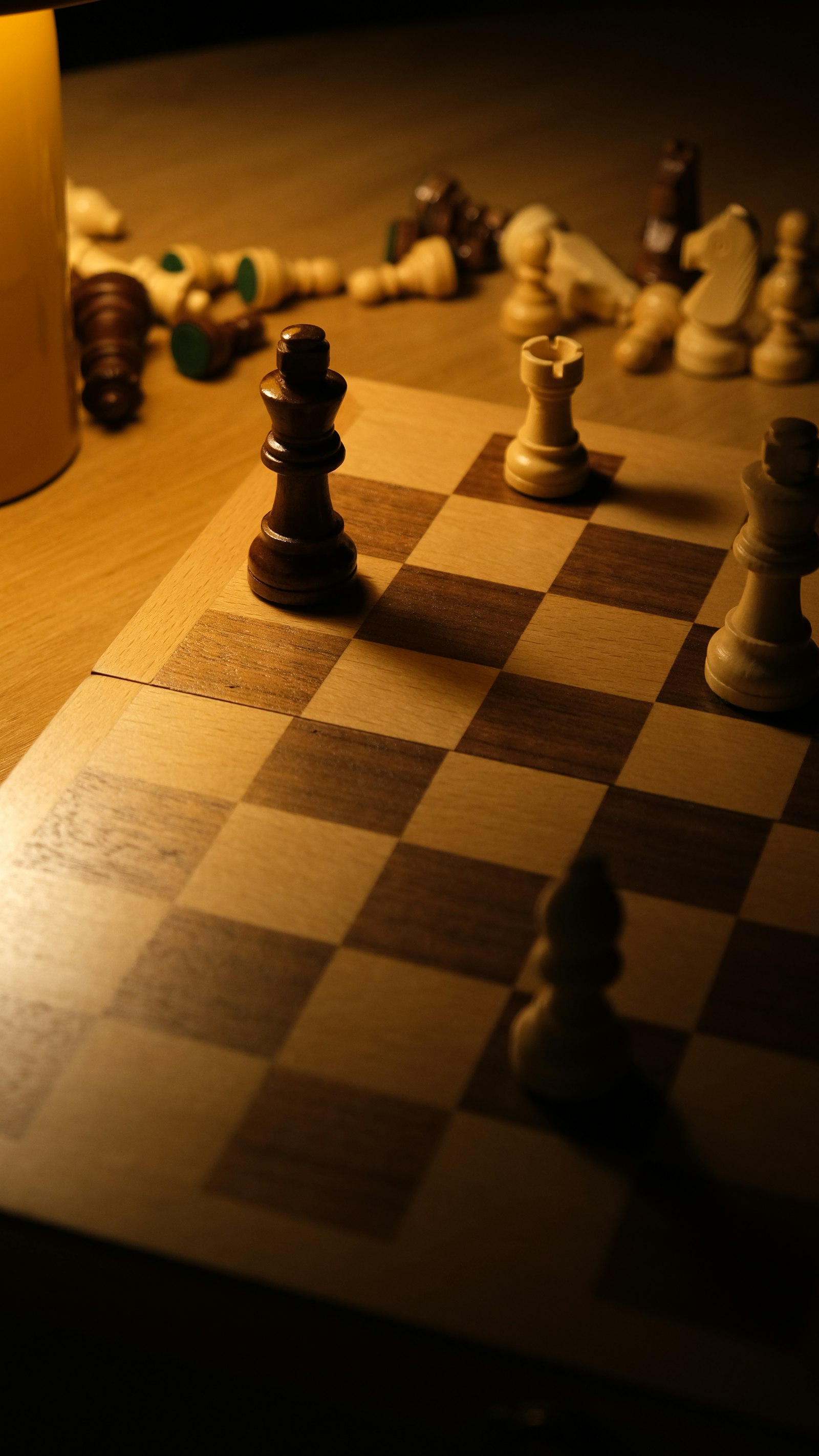 Chess pieces scattered across a board under warm light