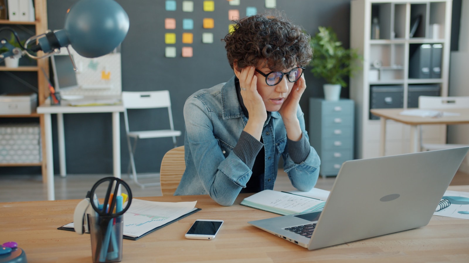 Office worker holding their head while staring at a laptop