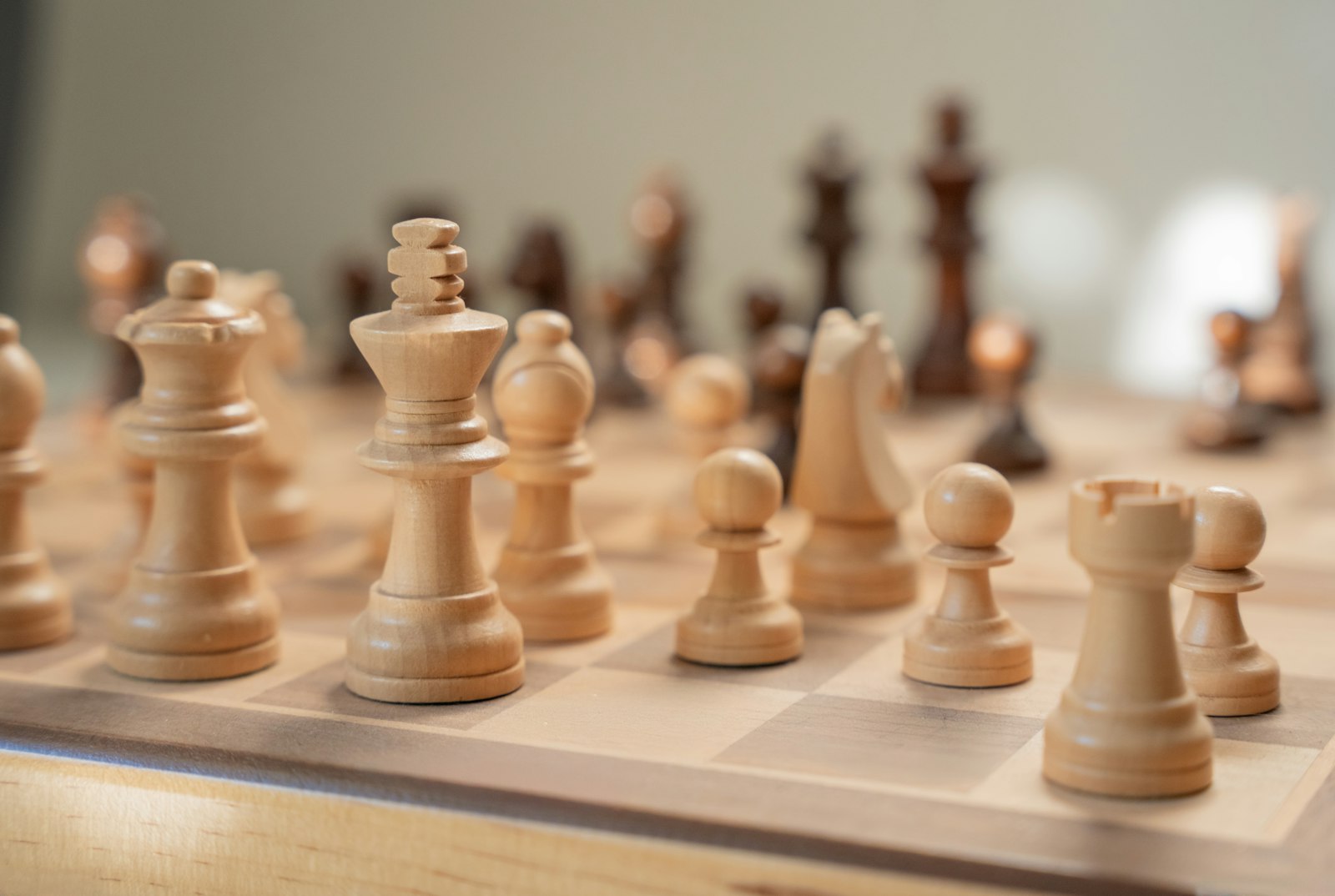 Wooden chess pieces arranged mid-game on a chess board